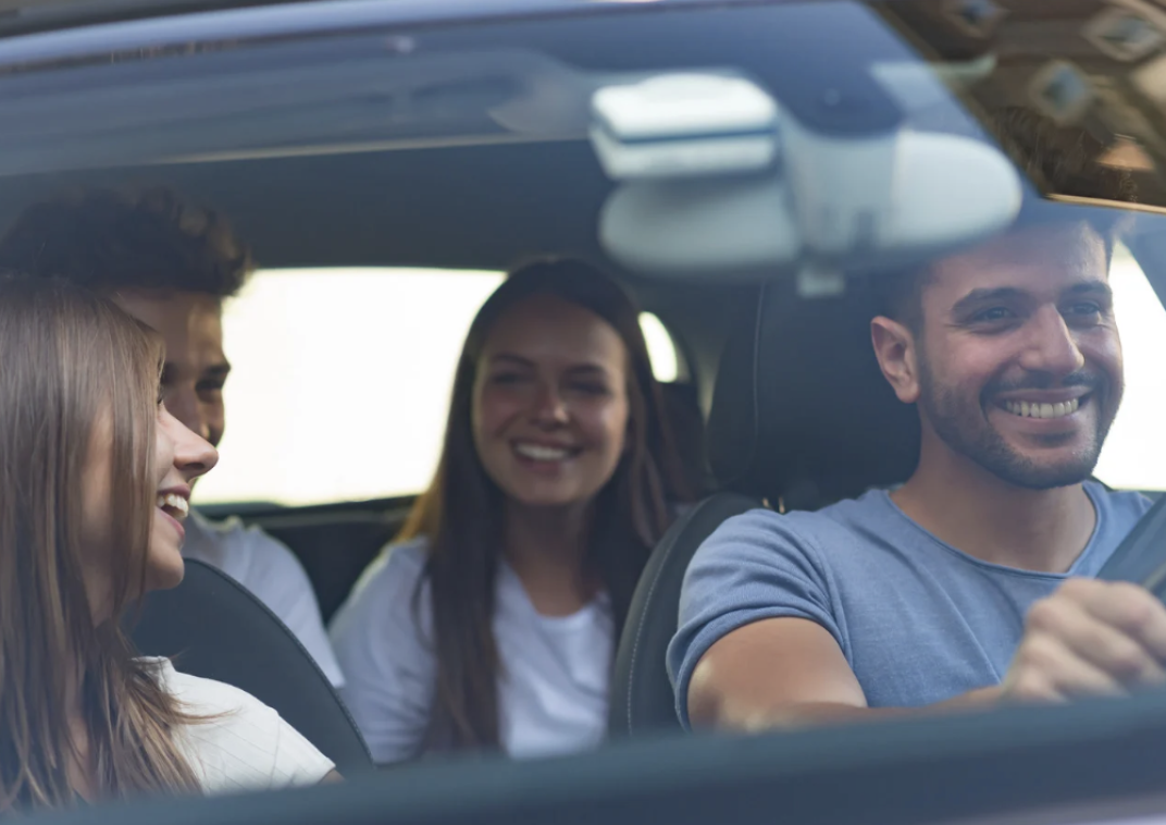 Vier personen lachend in een auto