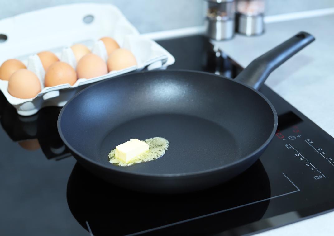 inductiekookplaat met boter in de pan en een doos eieren ernaast