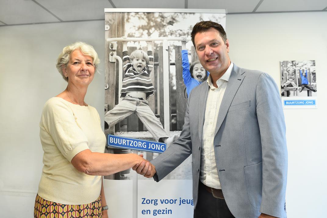 Monique van den Dries, bestuurder Buurtzorg Jong en wethouder Marco Bennink bezegelen de verlenging van hun samenwerking met een handdruk.